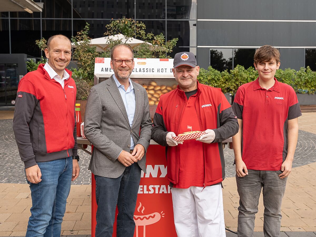 Thomas Ruhmer (Verkaufsleiter Fleisch und diplomierter Fleischsommelier), Mag. Dietmar Baurecht (Bezirksvorsteher), Marcel Homola (PENNY Vertriebsmanager & Fleischhauer) und PENNY Lehrling Simon vor dem PENNY Hotdog Stand am Wiener Westbahnhof